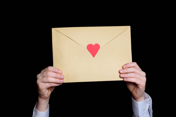 istock Large envelope with a red heart in children's hands. Close-up. Black background 1199834529