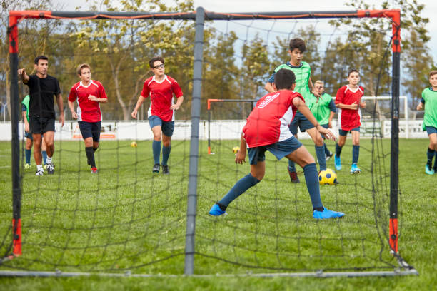 задний вид молодого футбольного вратаря, защищающегося от удара - goalie soccer soccer player teenage boys стоковые фото и изображения