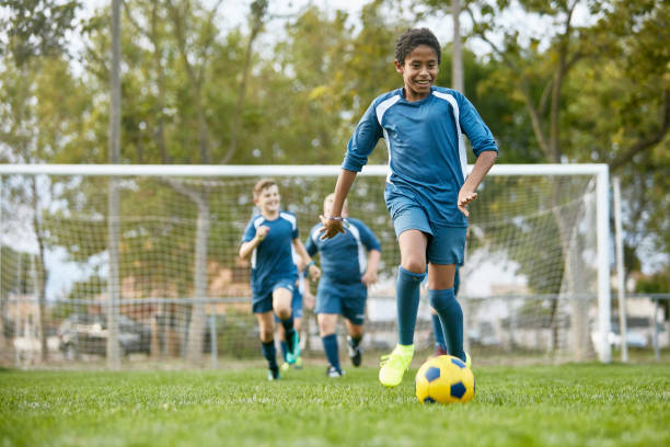 adolescente carrera mixta futbolista regateado lejos de compañeros de equipo - spanish and portuguese ethnicity fotos fotografías e imágenes de stock