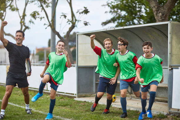 istock Victorious Footballers and Coach Cheering from Sidelines 1199836146