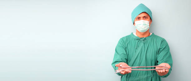 medico chirurgo asia maschile, chirurgo che mostra stetoscopio che indossa maschera chirurgo, su sfondo blu in studio con spazio di copia. - surgeon isolated paramedic operating room foto e immagini stock