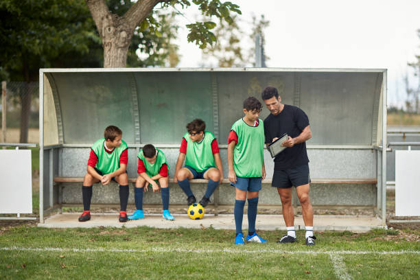 dojrzały mężczyzna trener i młody piłkarz strategizing - soccer bench soccer player sport zdjęcia i obrazy z banku zdjęć