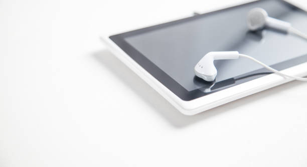 istock Tablet with a earphones on white desk. 1199837029