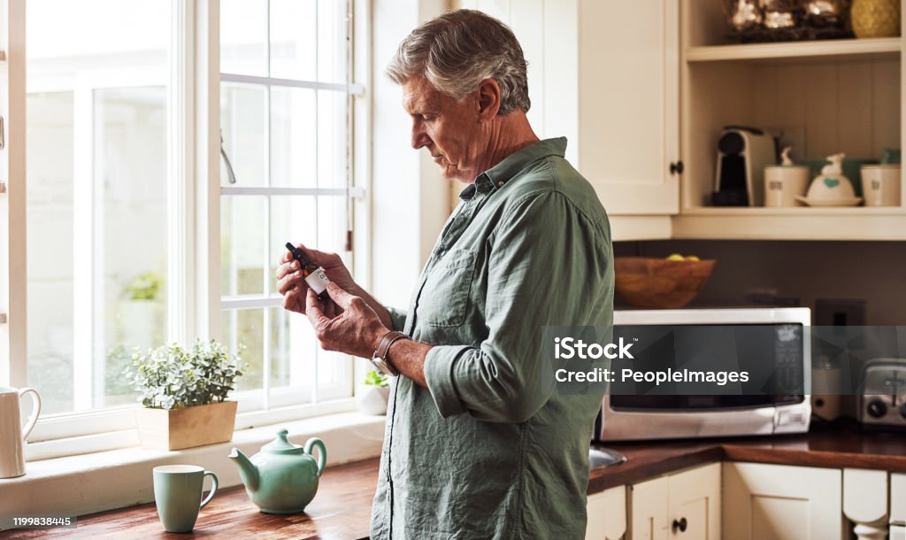 Don't take too much Cropped shot of a relaxed senior man preparing a cup of tea with CBD oil inside of it at home during the day Cannabidiol Stock Photo