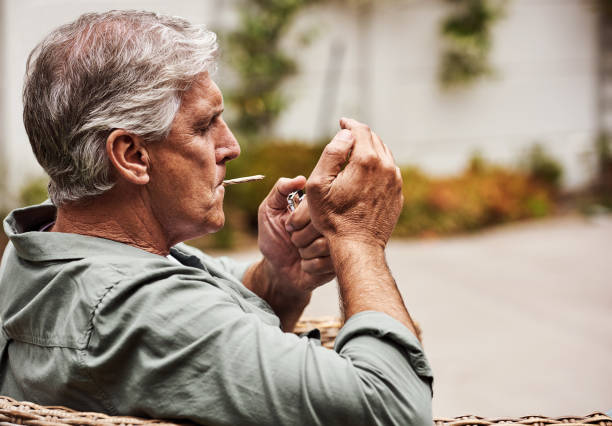 Time to light up Cropped shot of a relaxed senior man smoking a marijuana joint on his own inside of his garden at home during the day pitter stock pictures, royalty-free photos & images