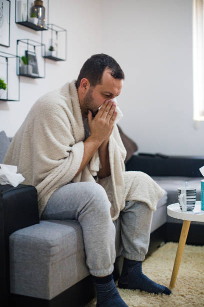 istock Man blowing his nose sick in bed 1199839615