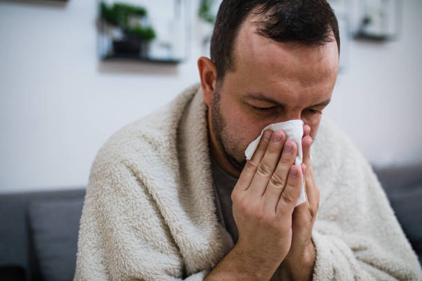 istock Man blowing his nose sick in bed 1199839735