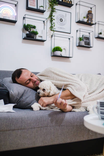 istock Sick man in bed checking fever with thermometer 1199839934