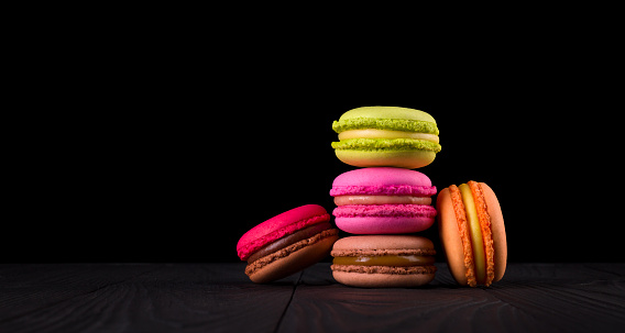 Heap of french colorful macaroon on wooden table isolated on black background with clipping path