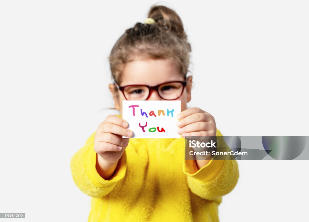 Adorable baby girl is holding a paper with a Thank you note. Silent communication concept. Adorable baby girl is holding a paper with a Thank you note. Silent communication concept Child Stock Photo