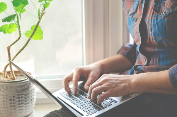 istock A man sits on a window sill with a laptop in his hands and works 1199843638