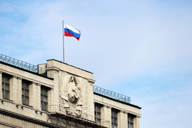 Russian flag on the parliament building in Moscow on background of blue sky and white clouds Facade of State Duma of Russia with soviet coat of arms, russian authority russian flag stock pictures, royalty-free photos & images