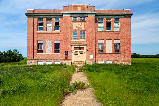 The old, abandoned Aneroid Consolidated School in Aneroid, Saskatchewan, Canada with teeter totters in the foreground