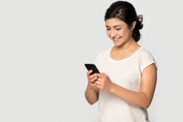 istock Happy young indian ethnicity lady standing aside copyspace with smartphone. 1199847393