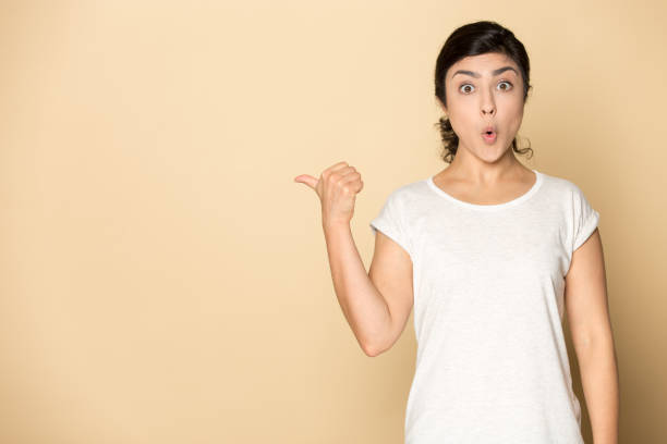istock Astonished female indian ethnic customer pointing finger aside on copyspace. 1199847398