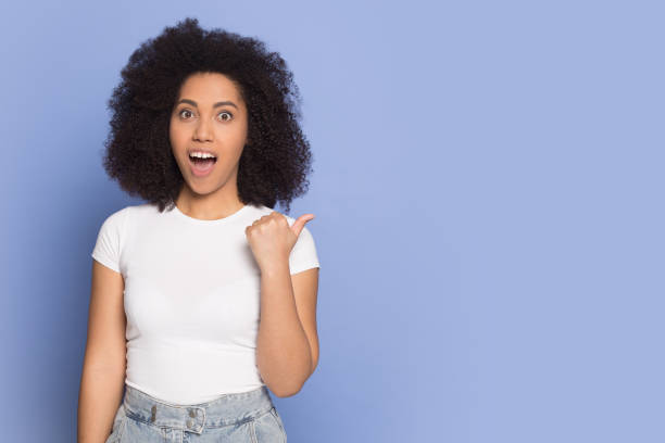 istock Surprised african american young lady pointing aside on copy space. 1199848725