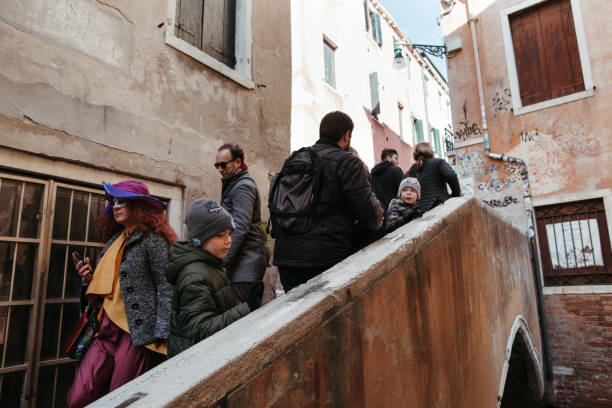 Venice, Italy. - February 22, 2019. People walk along the old streets and canals during the Venetian carnival.