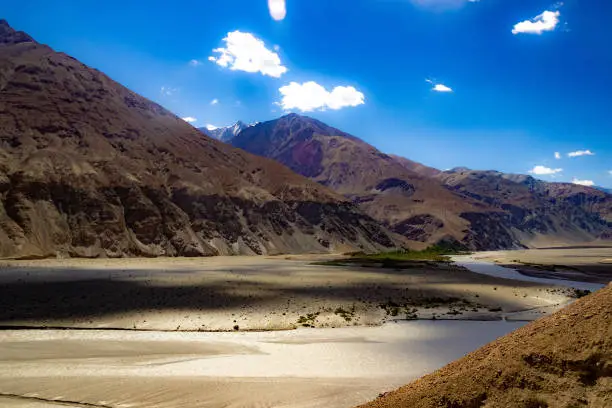 Photo of shades of cloud in High dynamic range image of barren mountain in a desert with river and deep blue sky in ladakh, Jammu and Kashmir, India