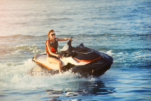 giovane donna caucasica sportiva adulta in moto d'acqua blu oceano al caldo tramonto serale. attività sportive estreme in spiaggia e svago - beautiful caucasian teenager running foto e immagini stock