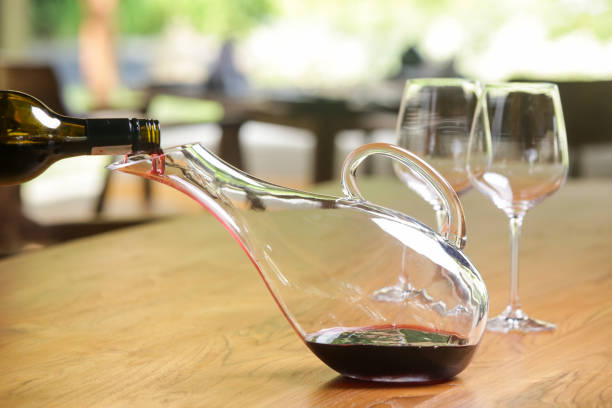 와인 디켄터, 와인 잔, 레드 와인. 디캔팅 와인은 퇴적물병이 병에 남아 있고 좋은 맑은 와인을 얻고 두 번째로 일상적인 이유를 얻을 수 있도록 와인을 통조림하는 것입니다. - wine decanter elegance pouring 뉴스 사진 이미지