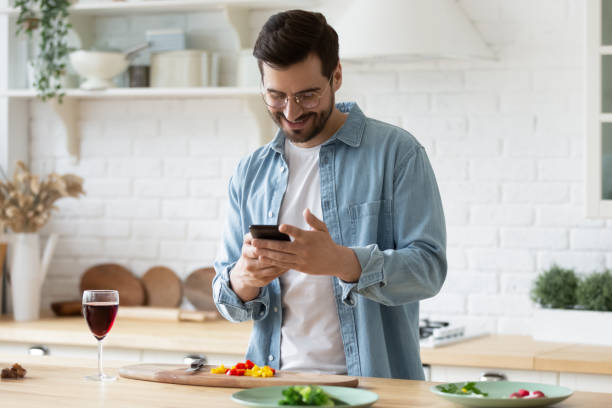 istock Happy millennial guy in eyeglasses web surfing recipe for meal. 1199863487