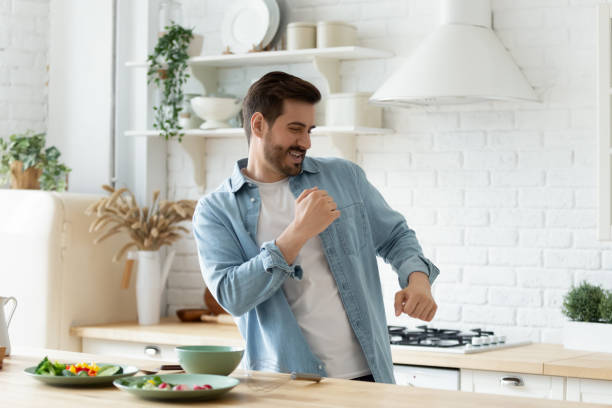 istock Joyful young man dancing at modern kitchen, preparing healthy food. 1199863497