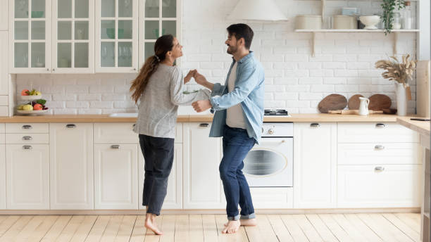 キッチンの木製の床で裸足で踊る幸せな家族のカップル。 - humor men laughing teenager ストックフォトと画像