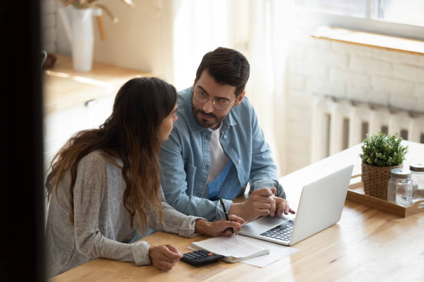istock Focused family couple discussing monthly expenses, using computer banking applications. 1199863513