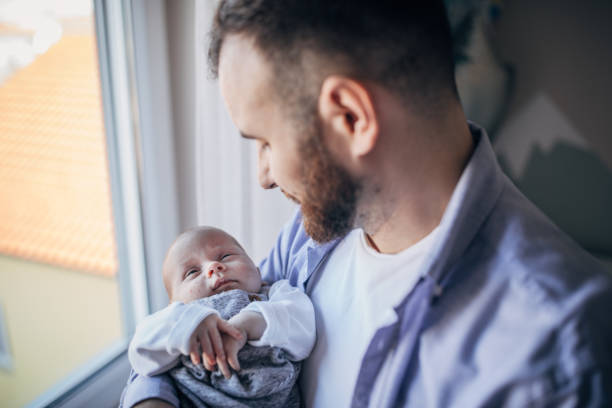 istock Father holding his baby boy in arms at home 1199863607
