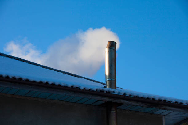 house chimney with smoke in winter scene. clear blue sky in the background