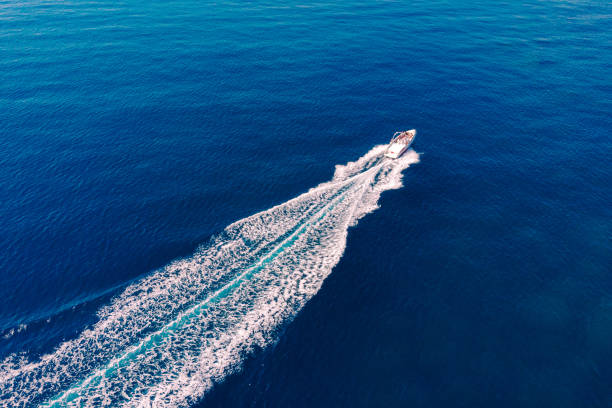 vista dall'alto del mare e una barca bianca ad alta velocità in una giornata di sole. concetto di vacanza estiva al mare. bellissimo paesaggio marino in estate. - recreational boat motorboat speedboat aerial view foto e immagini stock