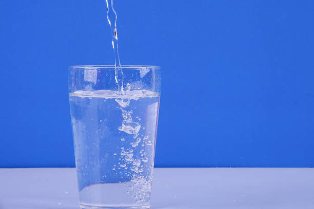 istock Water splashing from glass isolated on a blue background. 1199868854