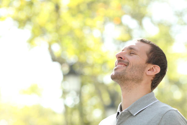 istock Happy man breathing deep fresh air standing in a park 1199871481