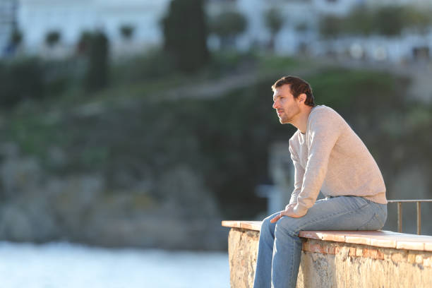 istock Pensive man looking away sitting in a balcony 1199871676