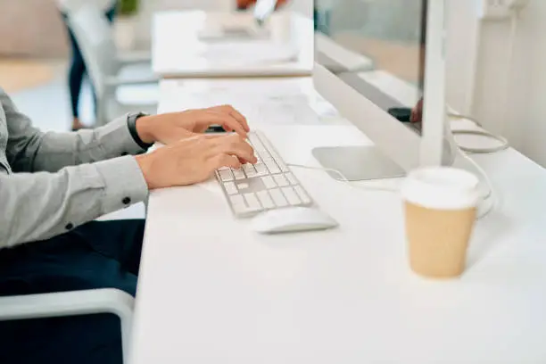 Cropped shot of an unrecognizable businessman sitting and using his computer in a coworking office space