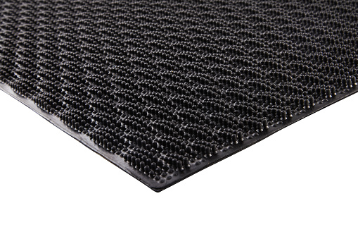 Black rubber entrance mat isolated on white background. Cellular rubber mat for dirt removal. Welcome carpet, close up