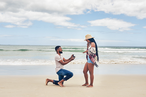 Shot of a young man proposing to his girlfriend at the beach