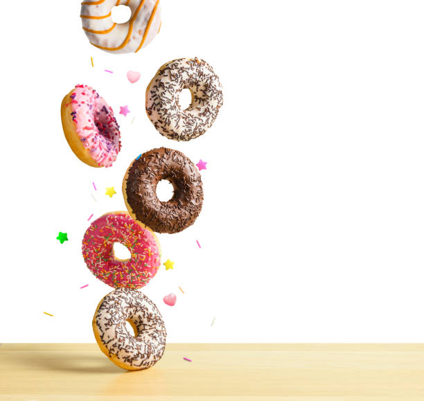istock Flying donuts isolated on white. Mix of multicolored sweet doughnuts with sprinkel falling on the table 1199877392