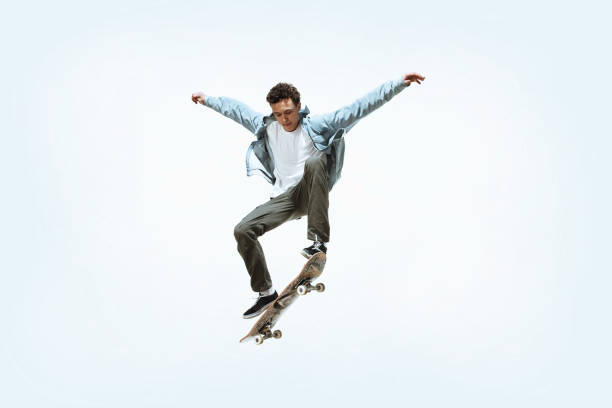Caucasian young skateboarder riding isolated on a white background Caucasian young skateboarder riding isolated on a white studio background. Man in casual clothing training, jumping, practicing in motion. Concept of hobby, healthy lifestyle, youth, action, movement. skateboarding stock pictures, royalty-free photos & images