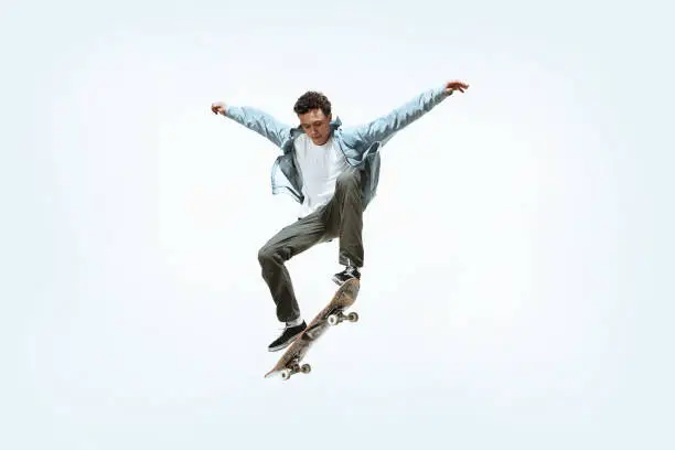 Photo of Caucasian young skateboarder riding isolated on a white background