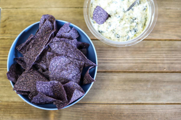 A bowl  of organic blue corn tortilla chips with spinach dip on the side