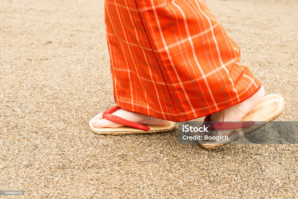Feet of Japanese Woman Walking Outdoors on a Dirt Road This is a low angle photograph of a Japanese woman’s feet as she walks  outdoors on a  dirt road wearing traditional Geta sandals. Foot Stock Photo