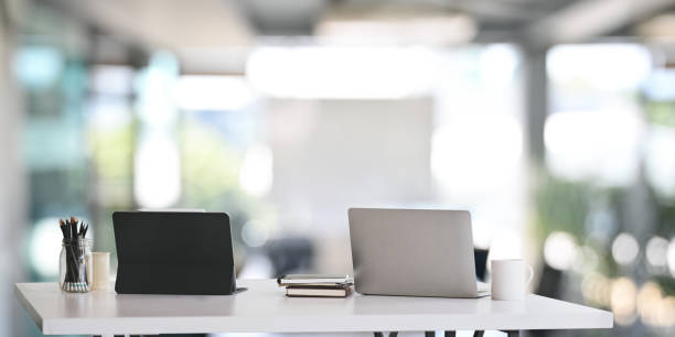 istock Office desk workspace with laptop, tablet and office supplies on white table in modern office. 1199885265