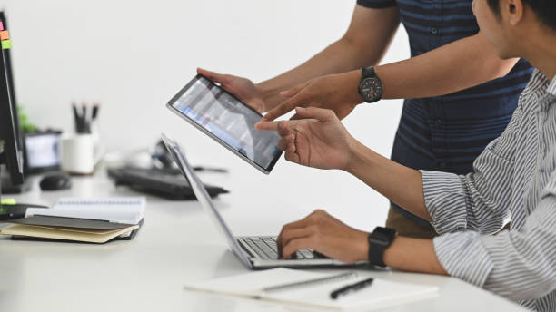 istock Side view shot of Young confidence businessmen discussing project on digital tablet while sitting in the modern office. 1199885390