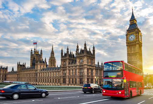 Houses of Parliament with Big Ben and double-decker bus on Westminster bridge at sunset, London, UK