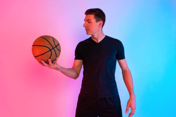 istock Young athletic man, with basketball, posing on background with neon lights 1199887302