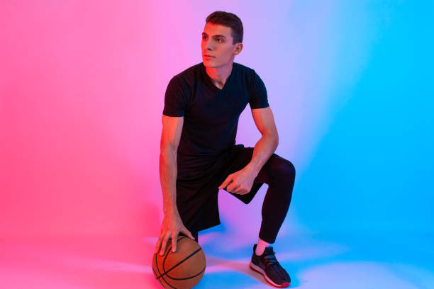 istock Young athletic man, with basketball, posing on background with neon lights 1199887360