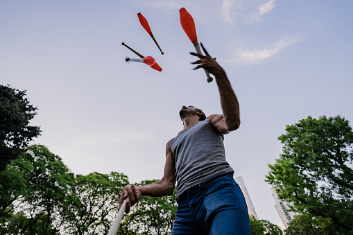 Argentinian mature man juggling with cones in public park. Puerto Madero, Buenos Aires, Argentina.