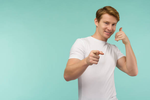 istock Call me. Handsome young smiling man looking at camera and gesturing mobile phone near face while standing against blue background 1199888644