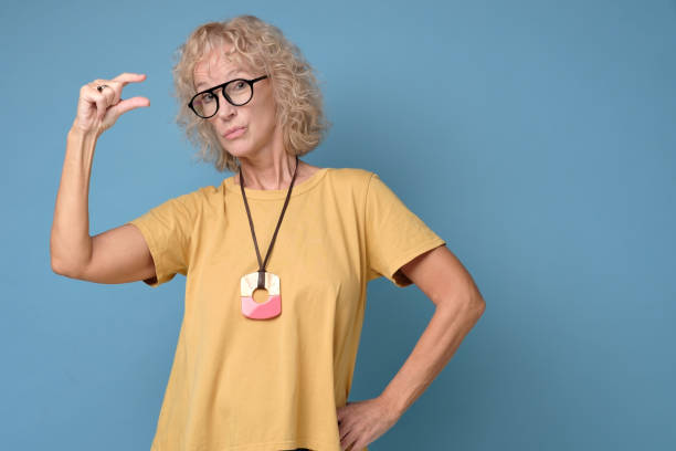 istock Pretty mature woman, shows very tiny object with fingers, demonstrates size 1199888654